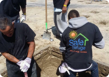 Four Safe Refuge volunteers wearing Safe refuge t-shirts and digging in a yard.