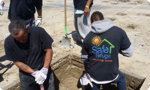 Four Safe Refuge volunteers wearing Safe refuge t-shirts and digging in a yard.