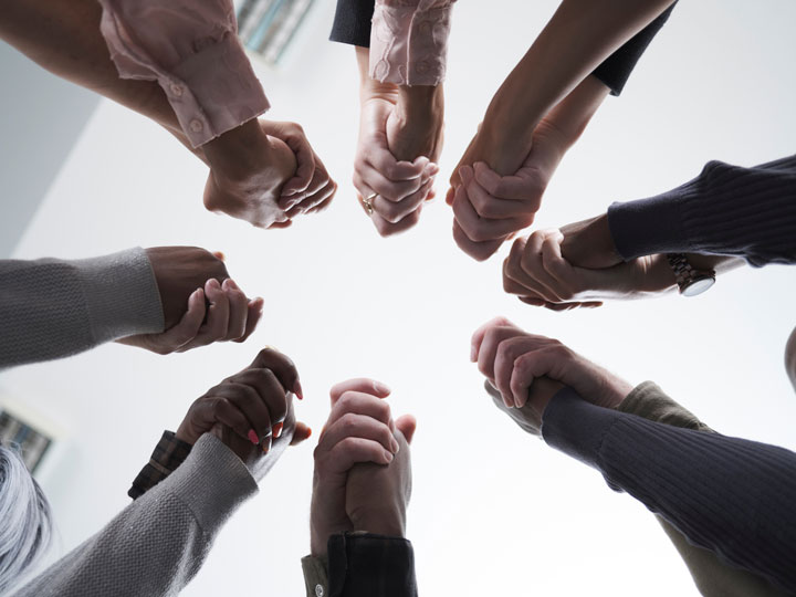 people holding hands with the camera angled below to show a circle