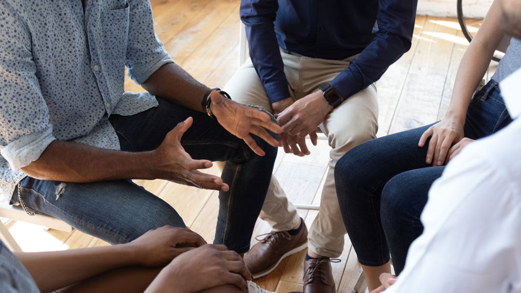 close of of hands and legs as people sit in a circle